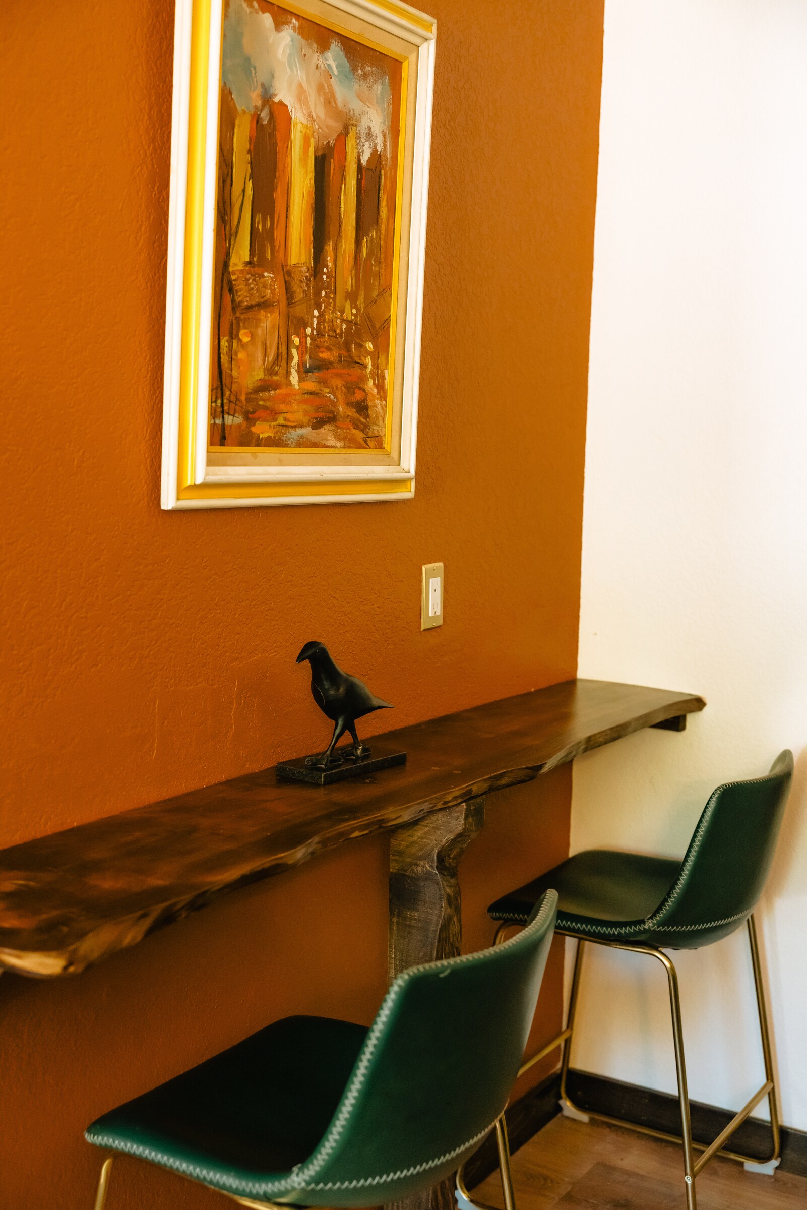 Live-edge counter and green leather barstools under an abstract painting — Alpen studio