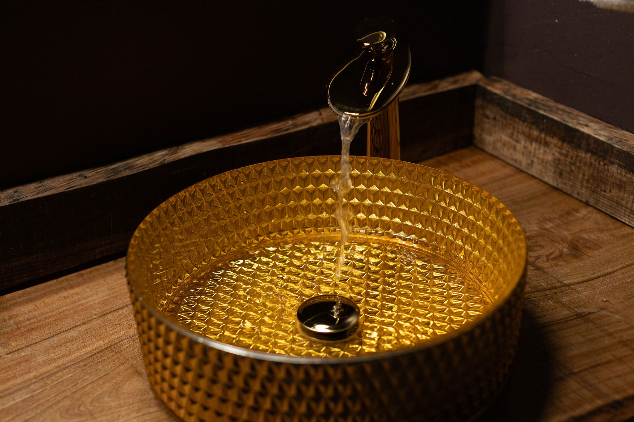 Faceted amber-glass vessel sink with gold faucet — Kinder Building spa bath